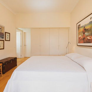 Imagen de habitación de invitados actual, grande, con paredes blancas, suelo de madera clara y suelo beige