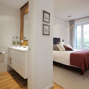 Imagen de dormitorio principal, actual, de tamaño medio, con paredes blancas, suelo de madera clara y suelo beige