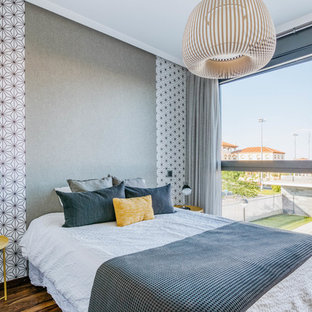 Imagen de dormitorio principal, actual, de tamaño medio, sin chimenea, con paredes grises, suelo de madera en tonos medios y suelo marrón