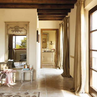 Design ideas for a country master bedroom in Other with beige walls, limestone floors and brown floor.