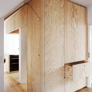 Foto di un armadio o armadio a muro unisex design con ante lisce, ante in legno chiaro, parquet chiaro e pavimento beige