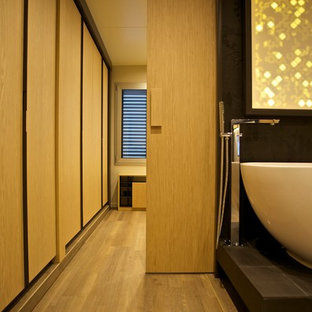 Cette image montre un grand dressing design pour un homme avec des portes de placard en bois clair et un sol en bois clair.