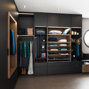 Inspiration pour un dressing design avec un placard à porte plane, des portes de placard noires et un sol marron.