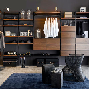 Inspiration pour un grand dressing room minimaliste pour un homme avec des portes de placard en bois sombre et béton au sol.