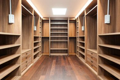 Cette photo montre un grand dressing room moderne en bois brun neutre avec un sol en bois brun.
