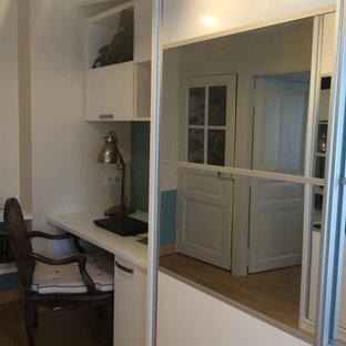Idée de décoration pour un dressing room design de taille moyenne et neutre avec un placard à porte plane, des portes de placard blanches, un sol en bois clair et un plafond en poutres apparentes.