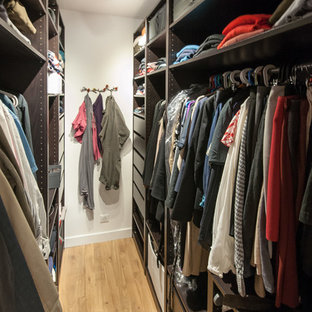 Idéer för att renovera ett litet funkis walk-in-closet för könsneutrala, med öppna hyllor, svarta skåp och mellanmörkt trägolv