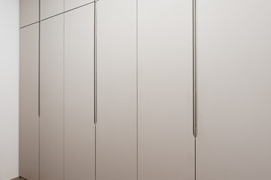 Inspiration pour un grand dressing design neutre avec un placard à porte affleurante, des portes de placard grises et parquet clair.