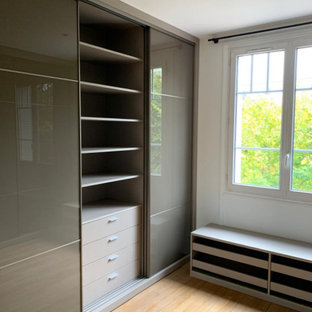 Foto di una cabina armadio unisex moderna di medie dimensioni con ante marroni, parquet chiaro e pavimento beige