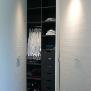 Réalisation d'un grand placard dressing design pour un homme avec un placard à porte plane, des portes de placard blanches et moquette.