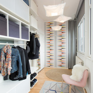 Inspiration pour un dressing room nordique de taille moyenne pour une femme avec des portes de placard blanches, un sol en bois clair et un sol beige.