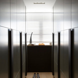 Aménagement d'un grand dressing contemporain neutre avec un placard à porte plane, des portes de placard en bois sombre et un sol en bois clair.