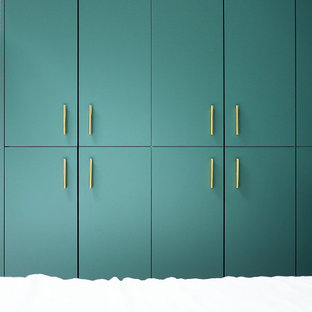 Inredning av ett modernt mellanstort walk-in-closet för könsneutrala, med luckor med profilerade fronter, blå skåp, ljust trägolv och beiget golv