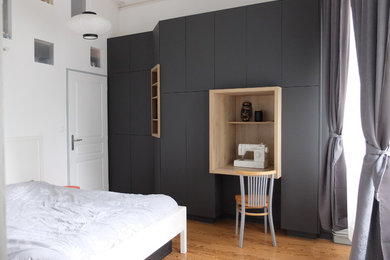 This is an example of a medium sized modern gender neutral standard wardrobe in Grenoble with medium hardwood flooring, brown floors, flat-panel cabinets and grey cabinets.