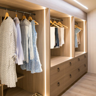 Exemple d'un dressing et rangement méditerranéen pour une femme avec un placard à porte plane, des portes de placard en bois brun, un sol en bois clair, un sol beige et un plafond voûté.