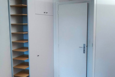 Cette image montre un petit placard dressing design neutre avec des portes de placard blanches et un sol marron.