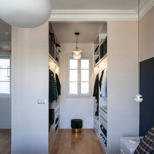 Idée de décoration pour un dressing design neutre avec un placard sans porte, des portes de placard blanches, un sol en bois brun et un sol marron.