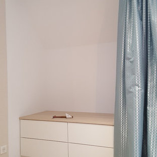 Foto de armario vestidor unisex, actual, de tamaño medio, con armarios con paneles lisos, puertas de armario blancas, suelo laminado y suelo beige