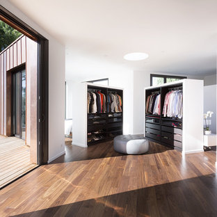 Cette photo montre un grand dressing room tendance pour un homme avec des portes de placard en bois sombre, un sol marron et un sol en bois foncé.