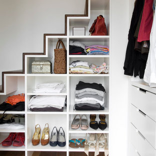 Exemple d'un placard dressing tendance de taille moyenne pour une femme avec un placard sans porte, des portes de placard blanches et un sol en bois brun.