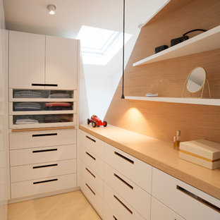 Réalisation d'un dressing design pour un homme avec un placard à porte plane, des portes de placard blanches et un sol en bois clair.