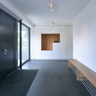 Großer Skandinavischer Eingang mit Foyer, weißer Wandfarbe, Betonboden, Einzeltür, schwarzer Tür und grauem Boden in Hamburg