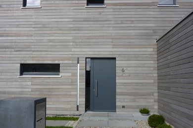 Mittelgroße Moderne Haustür mit brauner Wandfarbe, Betonboden, Einzeltür, grauer Haustür und grauem Boden in München