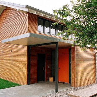 Esempio di un'ampia porta d'ingresso contemporanea con pareti marroni, una porta singola e una porta arancione