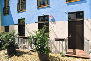 Große Haustür mit weißer Wandfarbe, hellem Holzboden, Einzeltür, Haustür aus Metall und braunem Boden in München