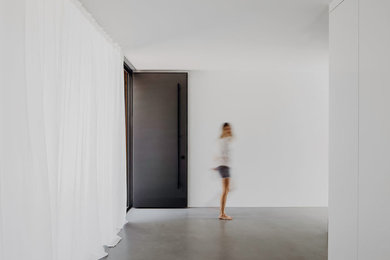 ミュンヘンにあるラグジュアリーな巨大なモダンスタイルのおしゃれな玄関ロビー (白い壁、コンクリートの床、黒いドア、グレーの床) の写真