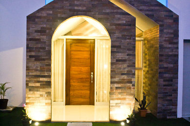 Esempio di una piccola porta d'ingresso minimal con pareti grigie, pavimento in gres porcellanato, una porta singola, una porta in legno chiaro e pavimento beige