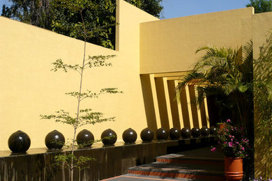 Imagen de entrada contemporánea grande con paredes amarillas, suelo de baldosas de terracota y suelo negro