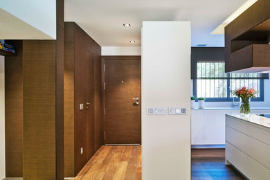 Diseño de hall actual de tamaño medio con paredes blancas y suelo de madera en tonos medios