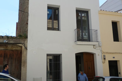 Diseño de entrada mediterránea pequeña con paredes blancas y puerta marrón