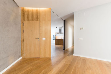 Inredning av en modern stor ingång och ytterdörr, med grå väggar, mellanmörkt trägolv, brunt golv, en enkeldörr och mellanmörk trädörr