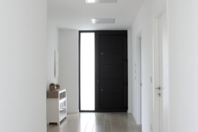 他の地域にあるモダンスタイルのおしゃれな玄関 (白い壁、磁器タイルの床、黒いドア、ベージュの床) の写真