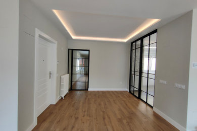 Modelo de hall clásico renovado grande con paredes grises, suelo de madera en tonos medios, puerta simple, puerta blanca y suelo marrón