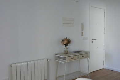 Diseño de vestíbulo escandinavo pequeño con paredes blancas, suelo laminado, puerta simple, puerta blanca y suelo marrón