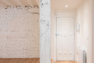 Cette image montre une entrée traditionnelle avec un couloir, un mur blanc, un sol en vinyl, une porte pivot, une porte blanche, un plafond en bois et un mur en parement de brique.