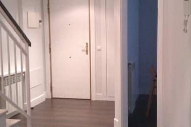 Modelo de hall minimalista pequeño con paredes grises, suelo de madera oscura, puerta simple y puerta blanca