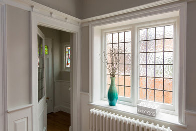 Réalisation d'un hall d'entrée craftsman de taille moyenne avec un mur gris, un sol en bois brun, une porte simple et une porte blanche.