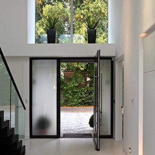 Immagine di un ingresso design con pareti bianche, una porta singola, una porta in vetro e pavimento bianco