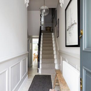 This is an example of a medium sized scandi hallway in London with white walls, painted wood flooring, a single front door, a blue front door and beige floors.