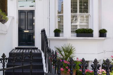 ロンドンにあるヴィクトリアン調のおしゃれな玄関ドア (白い壁、黒いドア) の写真