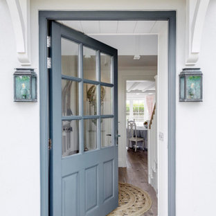 Aménagement d'une grand entrée bord de mer avec un couloir, un mur jaune, un sol en bois brun, une porte simple, une porte bleue, un sol marron, un plafond en lambris de bois et du lambris.