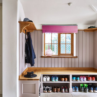This is an example of a small farmhouse boot room in London with white walls and grey floors.