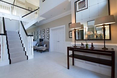 Photo of a large contemporary hallway in Surrey with beige walls, ceramic flooring, a single front door and white floors.