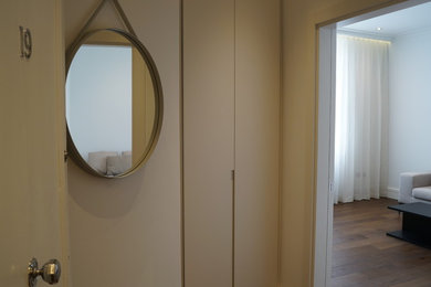 Diseño de hall actual de tamaño medio con paredes blancas, suelo de madera oscura, puerta simple, puerta blanca y suelo marrón
