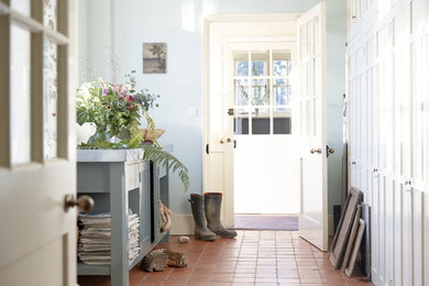 Photo of a classic entrance in Sussex with blue walls and terracotta flooring.