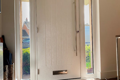 Foto de puerta principal minimalista con paredes blancas, suelo de madera oscura, puerta simple, puerta gris y suelo marrón